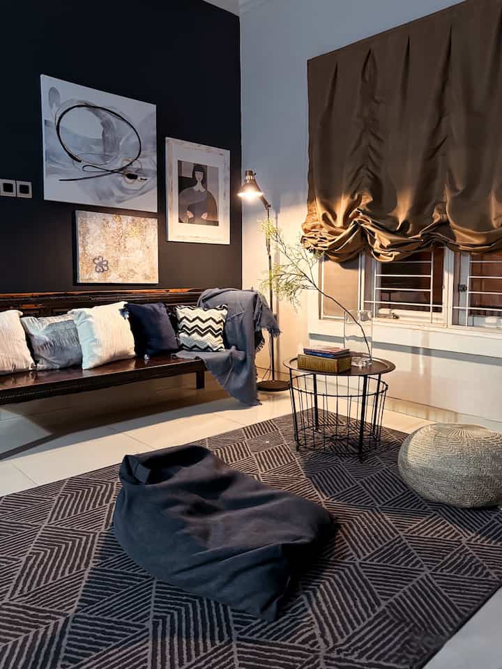 Living room in black and navy tones featuring wooden bench, bean bag, carpet, and wall decor with a modern and simple atmosphere
