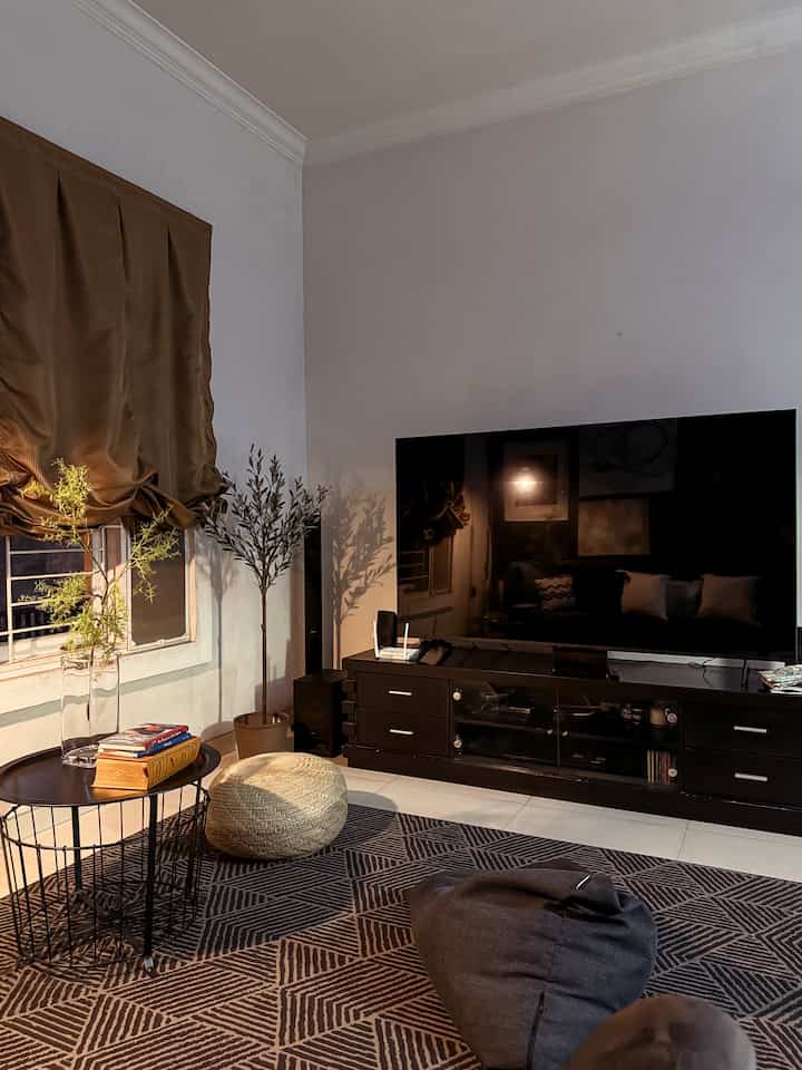Beige and black toned living room featuring a bean bag, side table, and TV storage cabinet with a cozy atmosphere