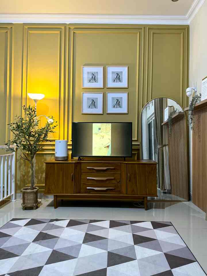 Gold-toned wall with wooden furniture in a living room featuring a large rug and floor lamp, creating a natural modern atmosphere