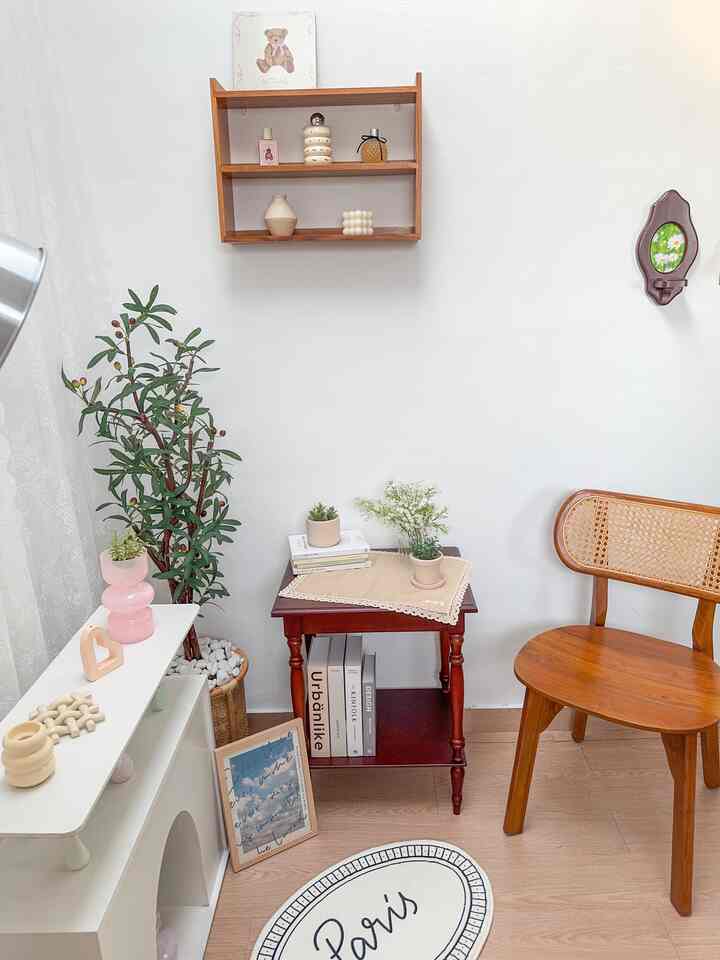 White-walled living room featuring wood-tone furniture, plants, and vases creating a natural and simple atmosphere