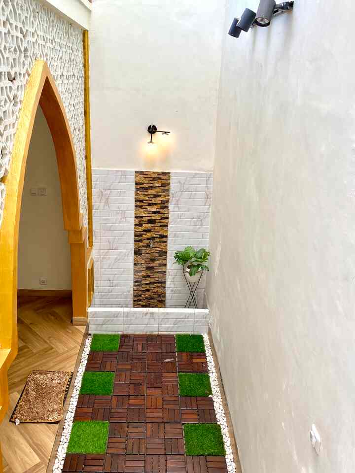 Natural-toned bathroom frontage featuring wood decking and artificial grass patches in a budget-friendly interior