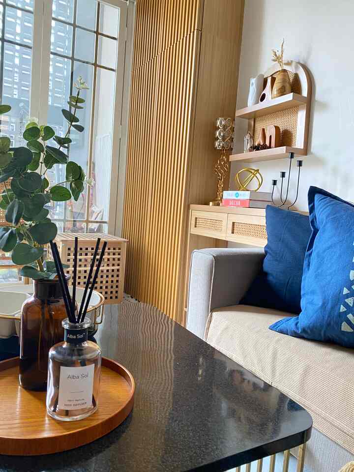Natural wood tone modern living room featuring a black side table with diffuser and decorative items, creating a cozy atmosphere