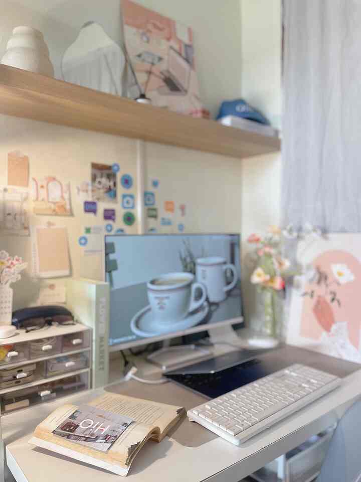 White-toned home office featuring a desk with monitor, pastel wall decor, and cozy accessories