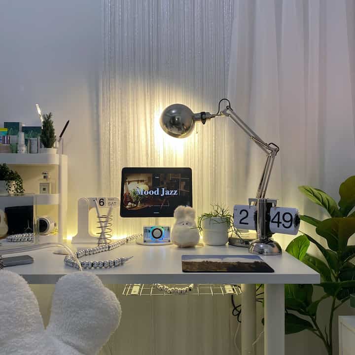 Modern and clean white and silver home office desk featuring plants and table lamp in a compact workspace