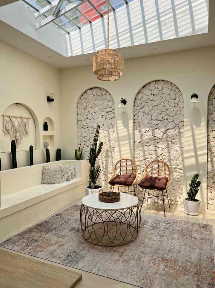 Bright living room with natural khaki tones and plants, featuring rattan chairs and a round coffee table creating a cozy atmosphere
