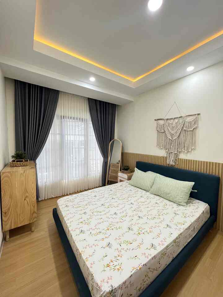 Navy and wood-tone bedroom featuring a floral bed and macrame wall hanging, creating a simple and natural atmosphere