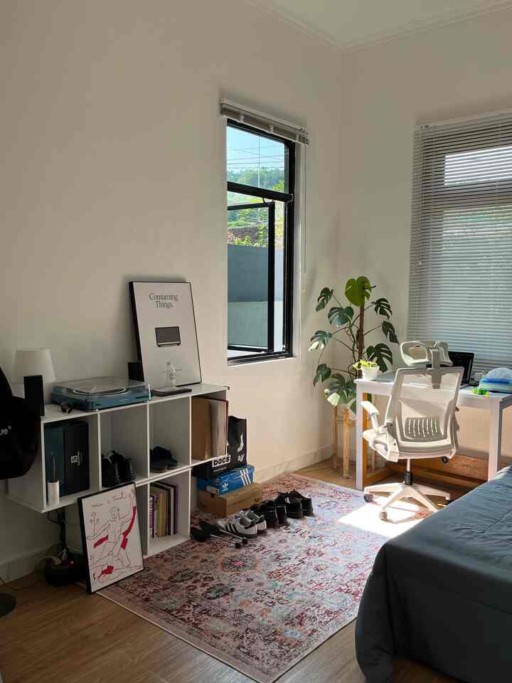 Small single household room in white and brown tones featuring a desk, office chair, and plant with cozy home office atmosphere