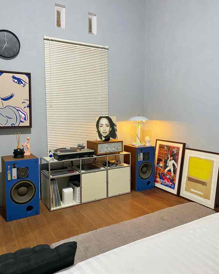 Mid-century modern bedroom with cream blinds, wood flooring, and distinctive blue speakers creating a cozy audio-focused space