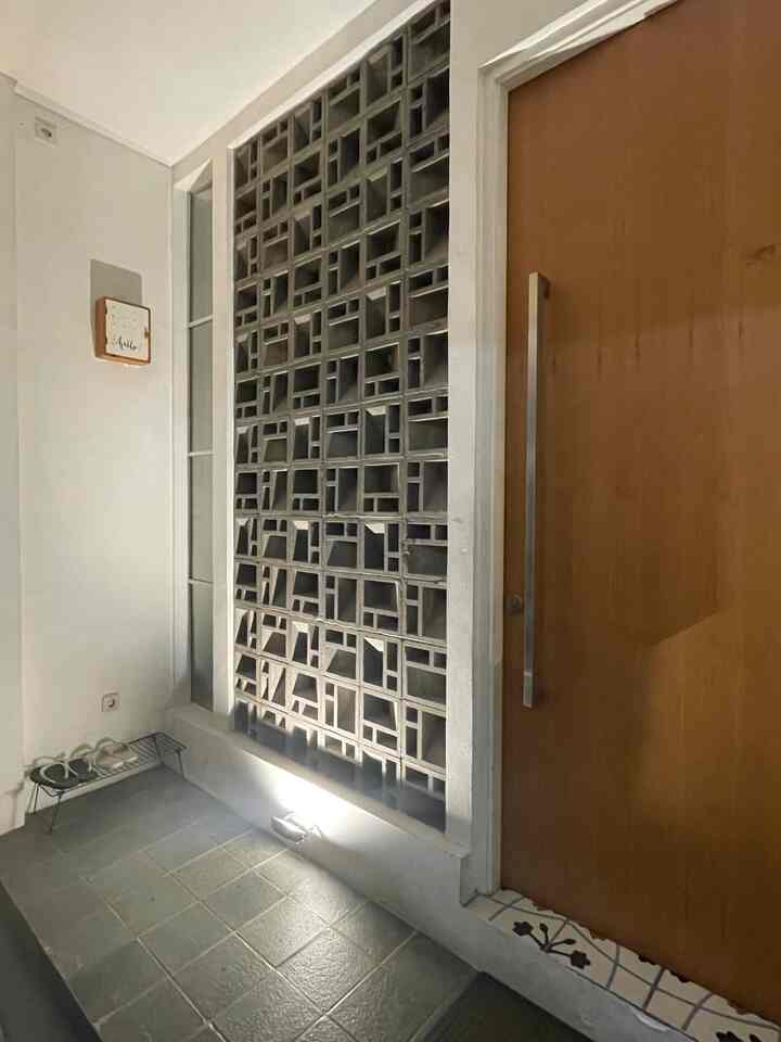 Gray tiled floor entrance with wood-toned door, shoe rack placed in corner for neat storage area