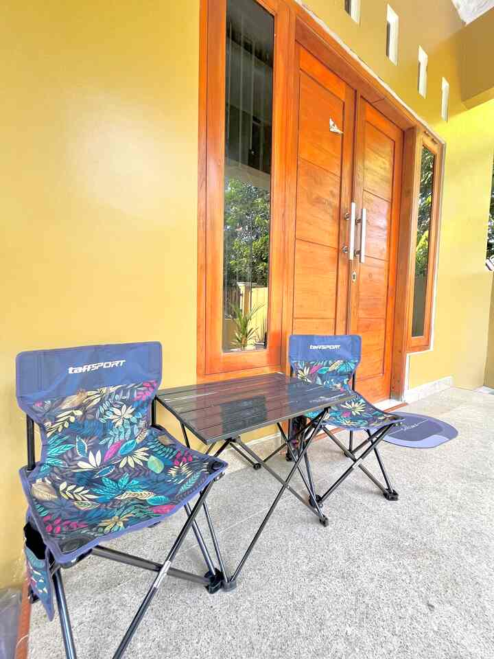 A veranda with yellow walls and brown wooden doors featuring two portable folding chairs and a foldable table
