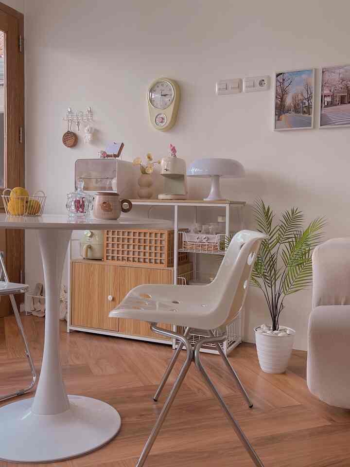 White and wood tone Korean-style living room featuring a round white dining table and vintage wall clock, creating a cozy atmosphere