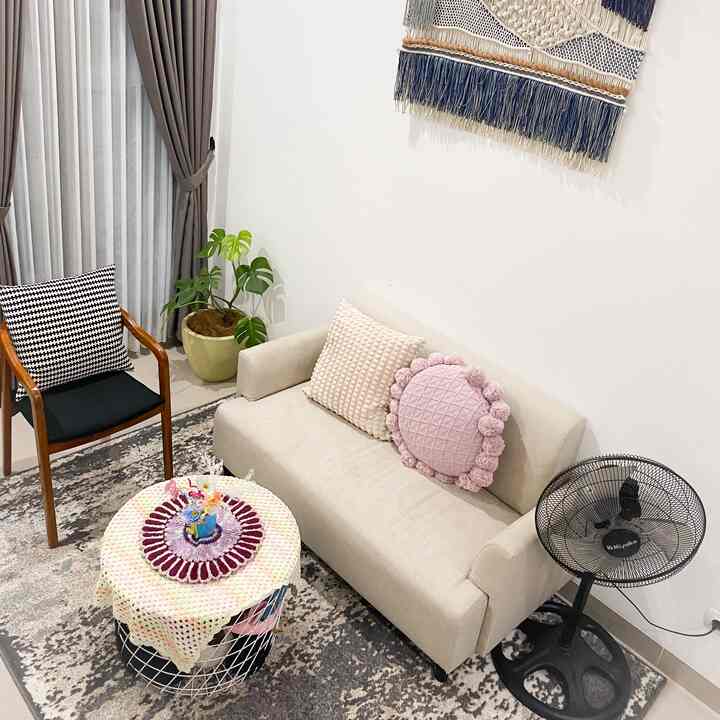 Beige-toned living room featuring a beige sofa, armchair, patterned carpet, and a potted plant in a cozy setting