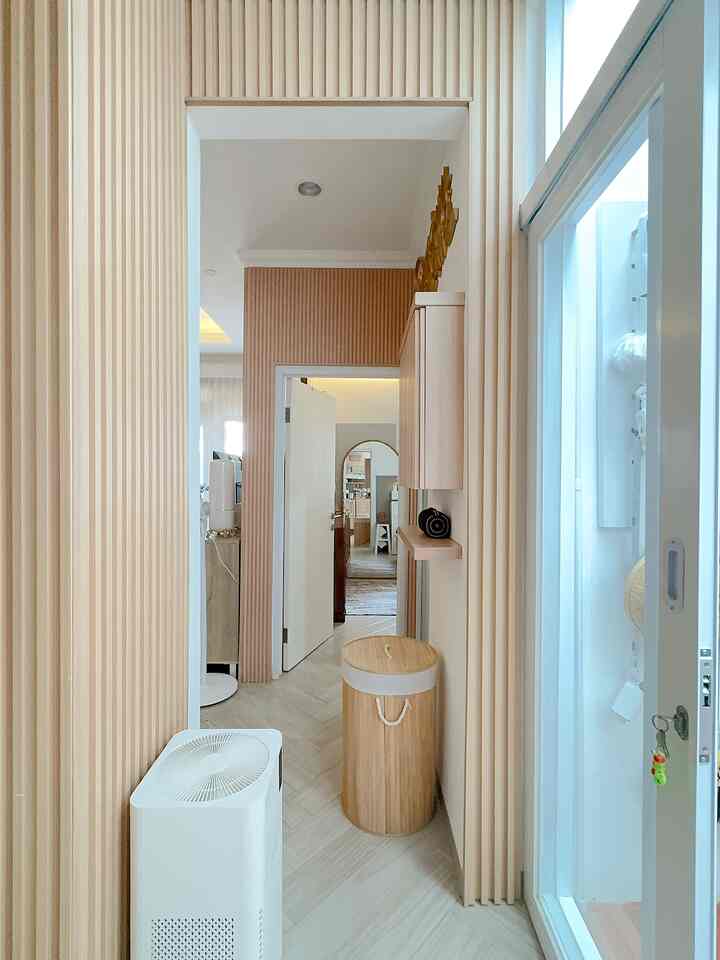 Beige and natural wood-toned narrow entrance featuring bamboo laundry basket and wood wall panels in a clean storage idea space