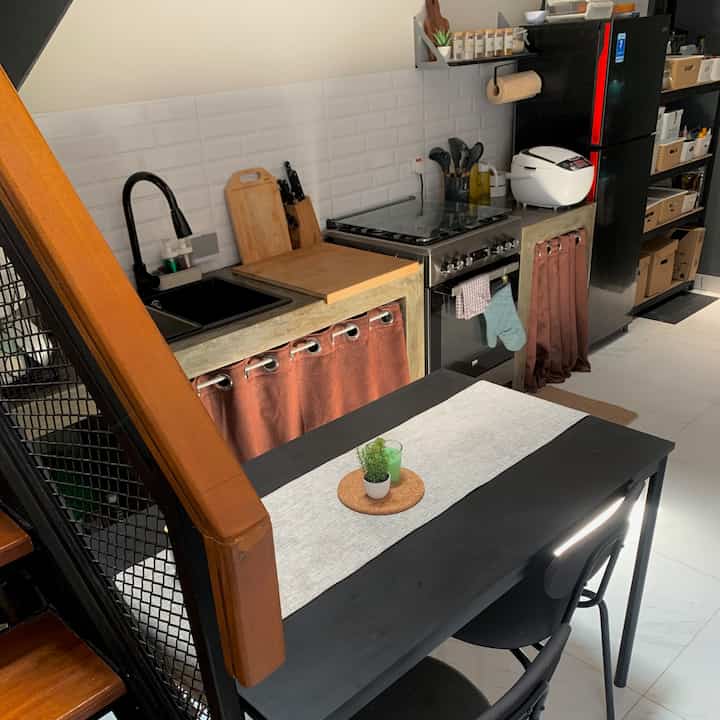 Brown and black toned compact kitchen for single household, neatly organized with storage and cooking utensils, featuring a natural atmosphere