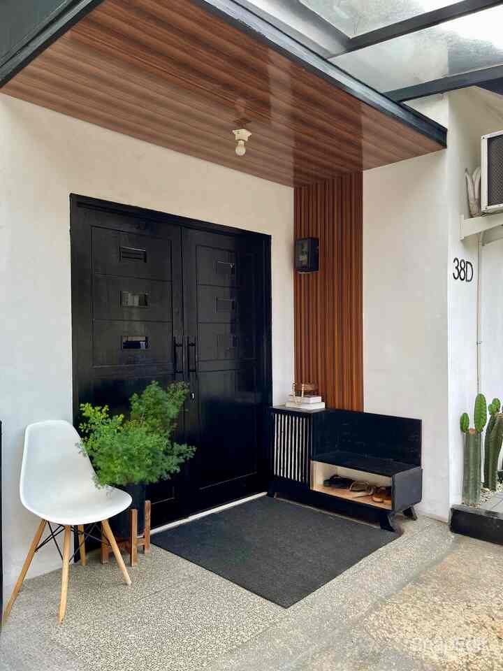 A modern entrance featuring black and wood tones, with a shoe cabinet and plants arranged on both sides for a clean aesthetic