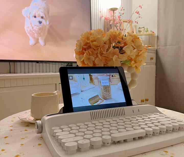 White and beige toned interior featuring a vase with flowers, teacup, and electronic device creating a cozy home cafe atmosphere