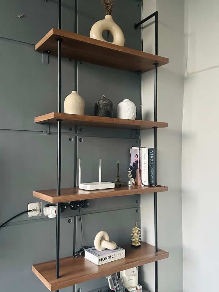 A space with navy walls featuring brown wooden shelves neatly arranged with decorative objects and books, creating a clean atmosphere