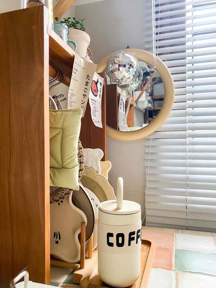 Warm wood tone kitchen space with white blinds, organized tableware and coffee accessories creating a cozy home cafe ambiance