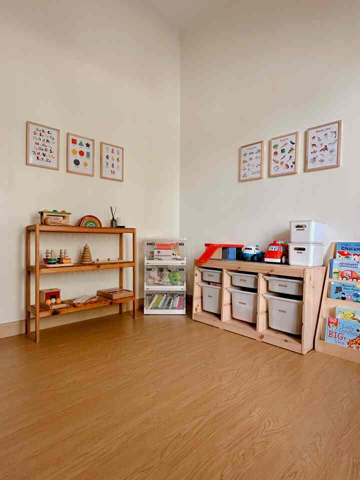 Kids' room with soft white walls and wood tone furniture, featuring toy storage units and educational posters in a tidy setting