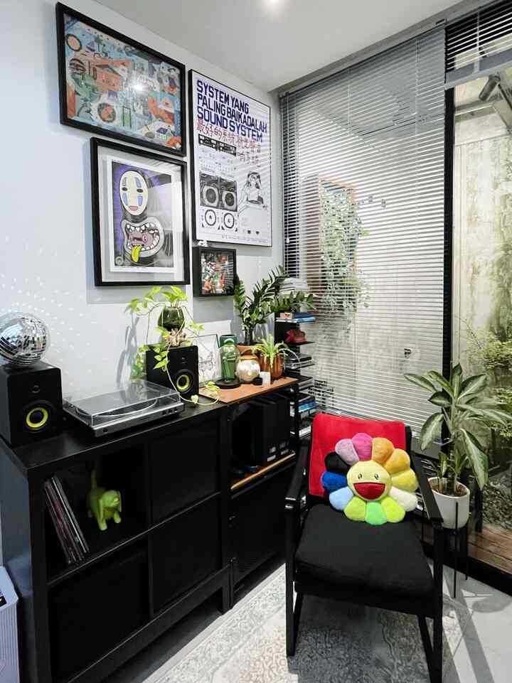 White walls and black shelves featuring various posters, plants, and a vintage turntable create an Instagrammable music listening space