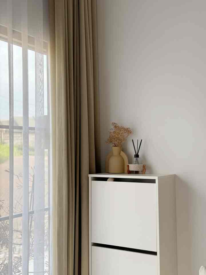 Clean entrance space featuring beige curtains and a white shoe cabinet
