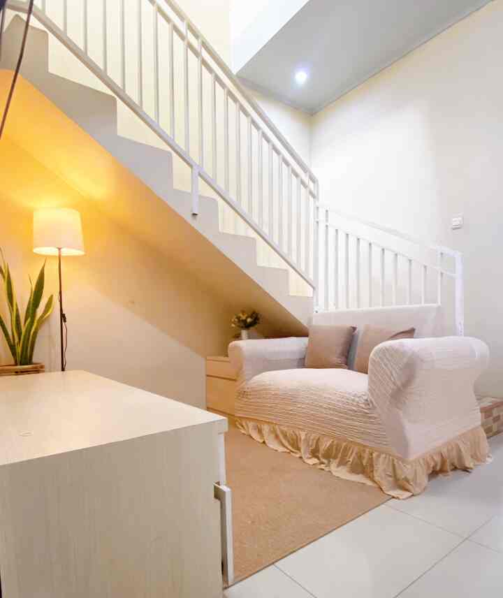 Beige and natural tone small living room under stairs featuring a sofa and floor lamp with cozy atmosphere