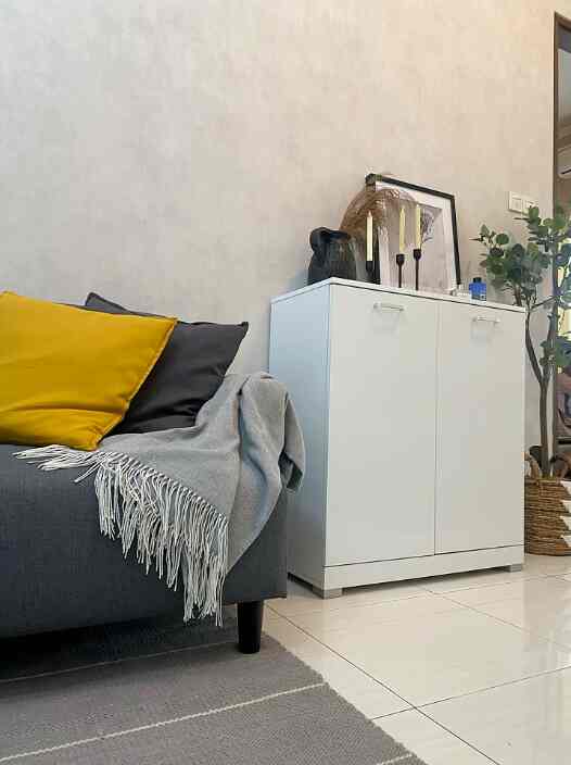 White and gray toned living room featuring a gray sofa and white storage cabinet in a simple natural setting
