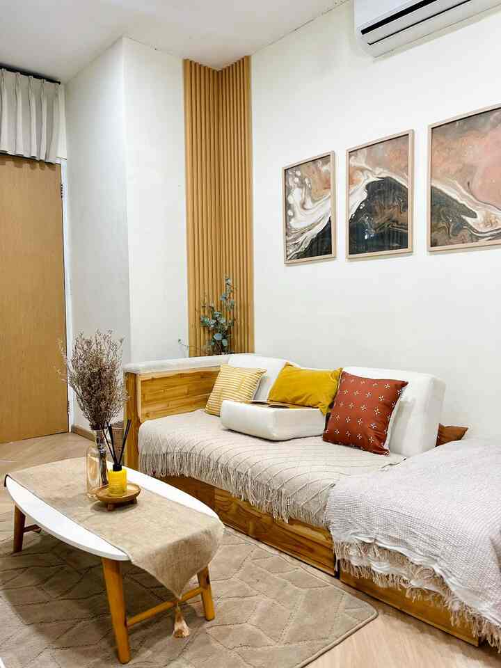 White walls and wood-toned furniture in a long narrow living room featuring a sofa, coffee table, and wall decor with a natural vibe