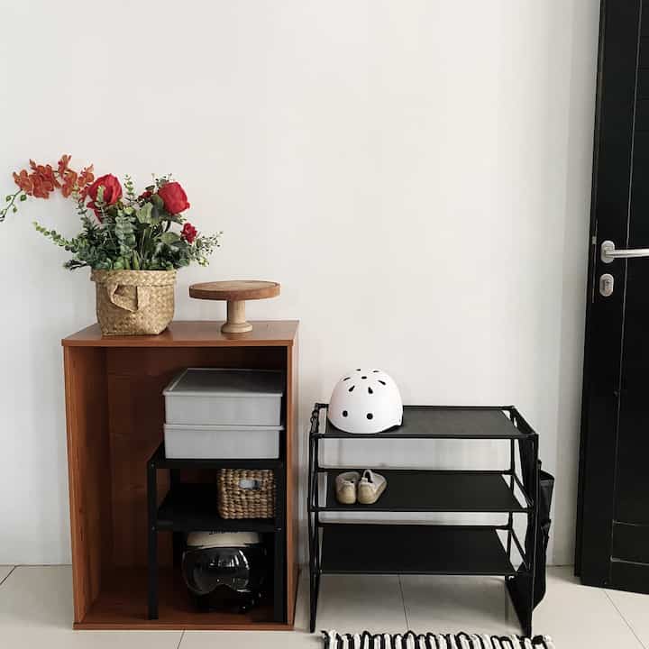 Bright white walls and floor with a wooden closet and black storage rack in a tidy entrance area