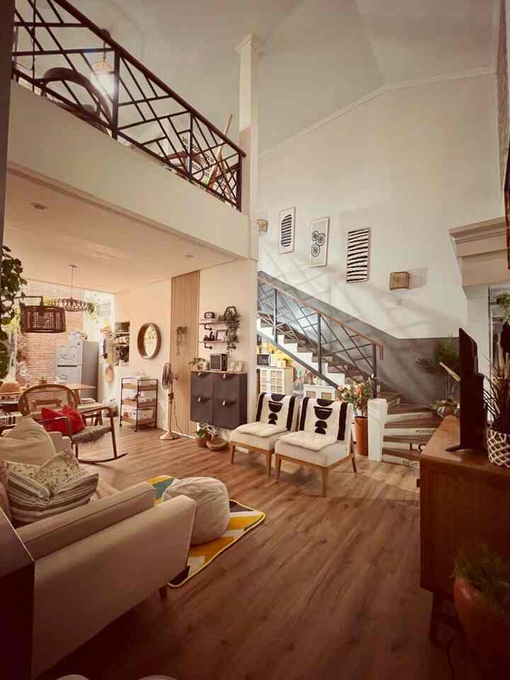 Natural tone living room and loft-style home featuring sofa, stairs, and wall decor creating a cozy interior