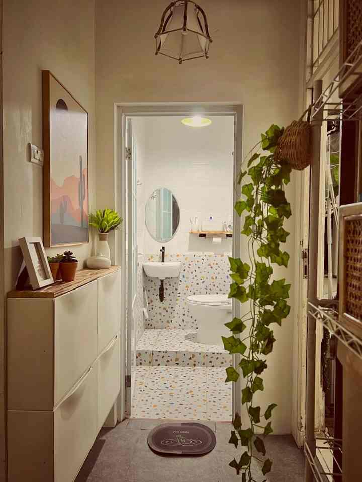 White and wood tone narrow entrance with shoe cabinet, plants, and artwork creating a natural atmosphere