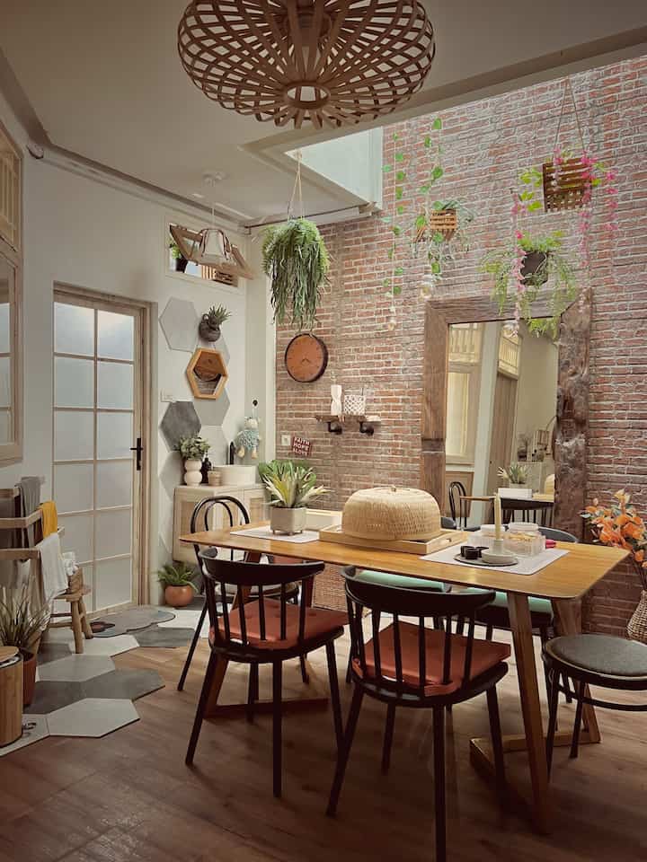 Dining room with exposed brick walls and wood tones, featuring natural plants and pendant lighting creating a warm atmosphere