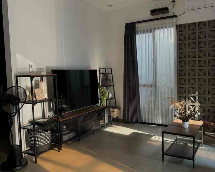 Modern and clean living room in black and white tones featuring black furniture, TV stand, and curtains