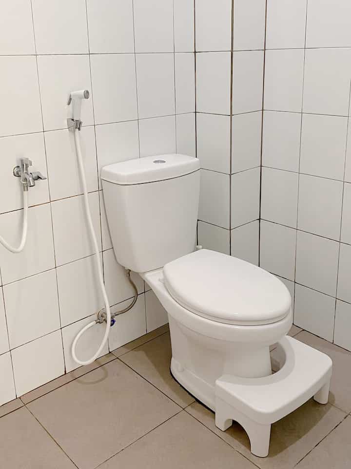 Clean bathroom space featuring white tiles and modern toilet with a white stool