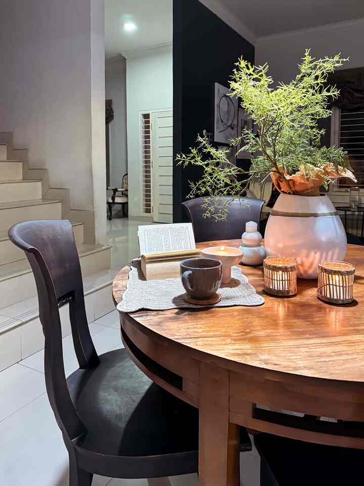 Warm brown round dining table with black dining chairs in a cozy dining area