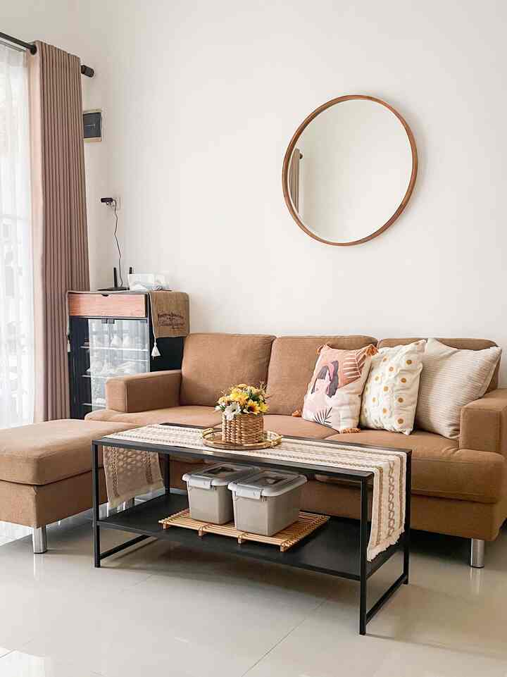 Natural living room featuring brown sectional sofa, round mirror, and table runner with warm tones