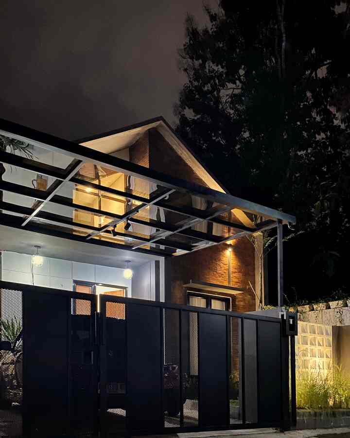 Industrial-style house exterior at night with illuminated lights and black metal gate