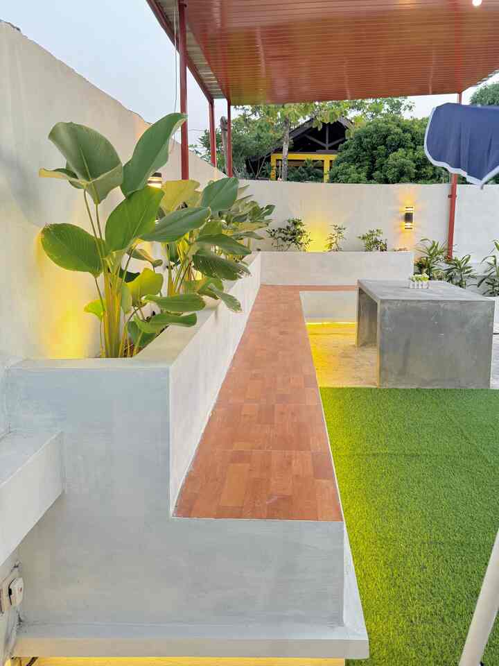 Green and white toned outdoor balcony space featuring plants and concrete table with a cozy atmosphere