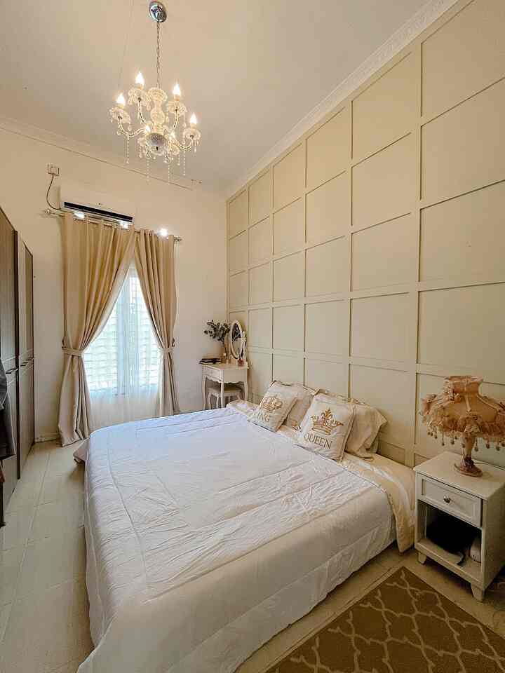 Beige and white toned bedroom featuring a large bed, vanity table, and chandelier creating an elegant atmosphere