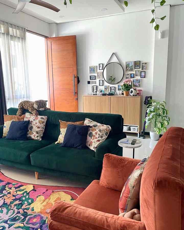 Bright white walls and natural wood furniture with colorful sofa cushions and greenery creating a cozy living room