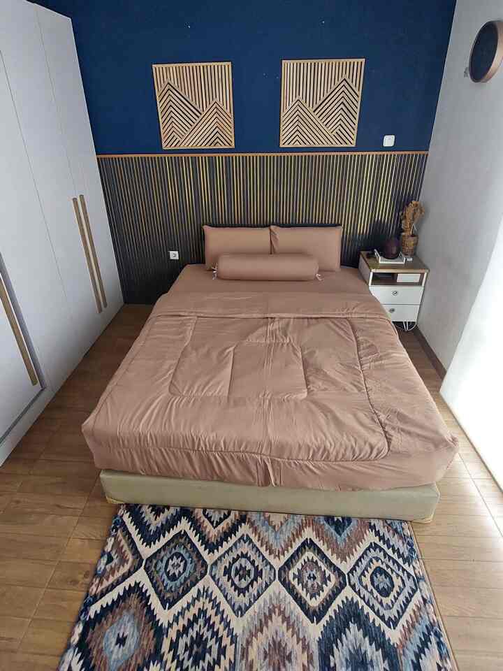 Dark blue and wood-toned bedroom featuring a bed and nightstand with a modern and cozy atmosphere