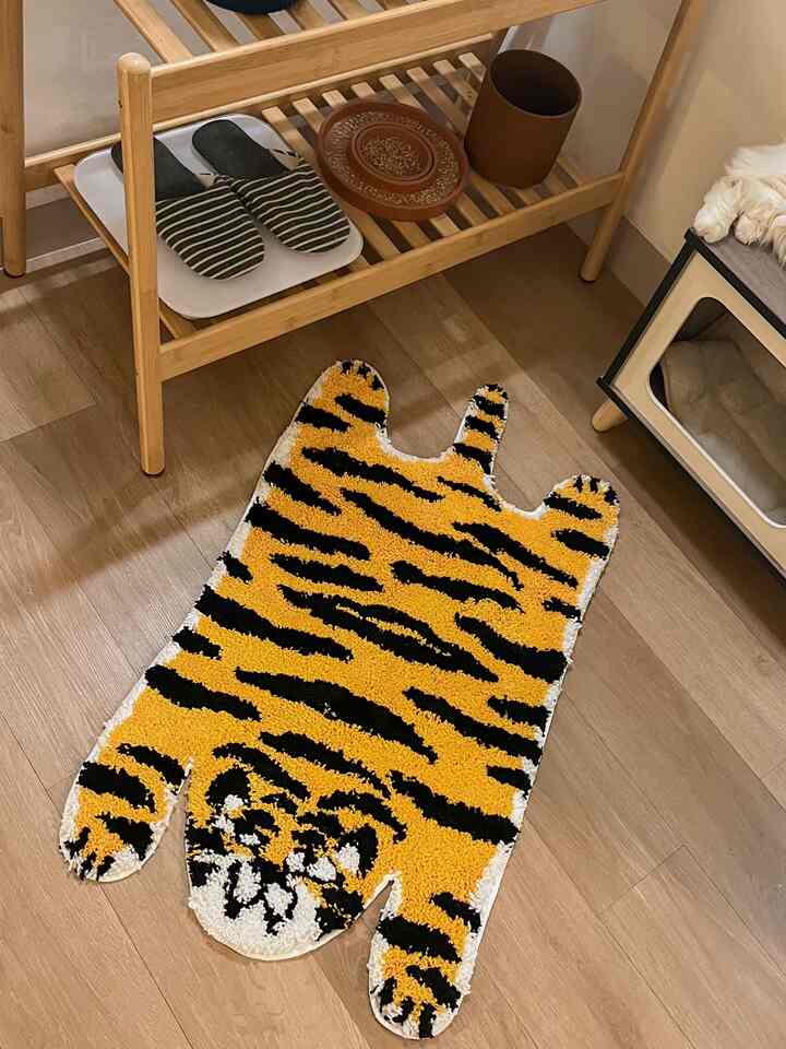Warm wood-tone floor space featuring a tiger-pattern rug and pet house, creating cozy living environment for pets