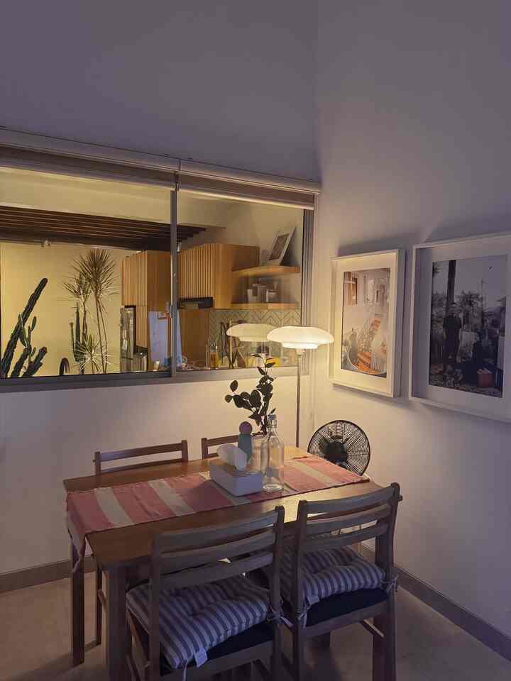 Dining room with wood tone furniture and white walls, featuring a pink table runner and table lamp creating a warm atmosphere