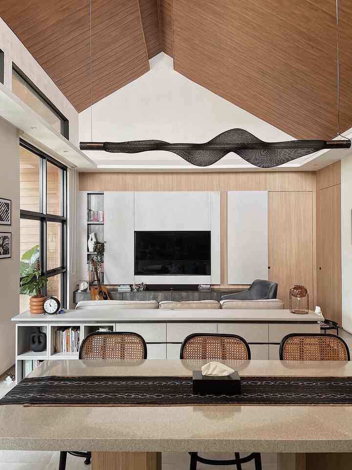 Natural wood tones and white walls define a living room featuring a sofa and TV stand in a clean open-plan layout