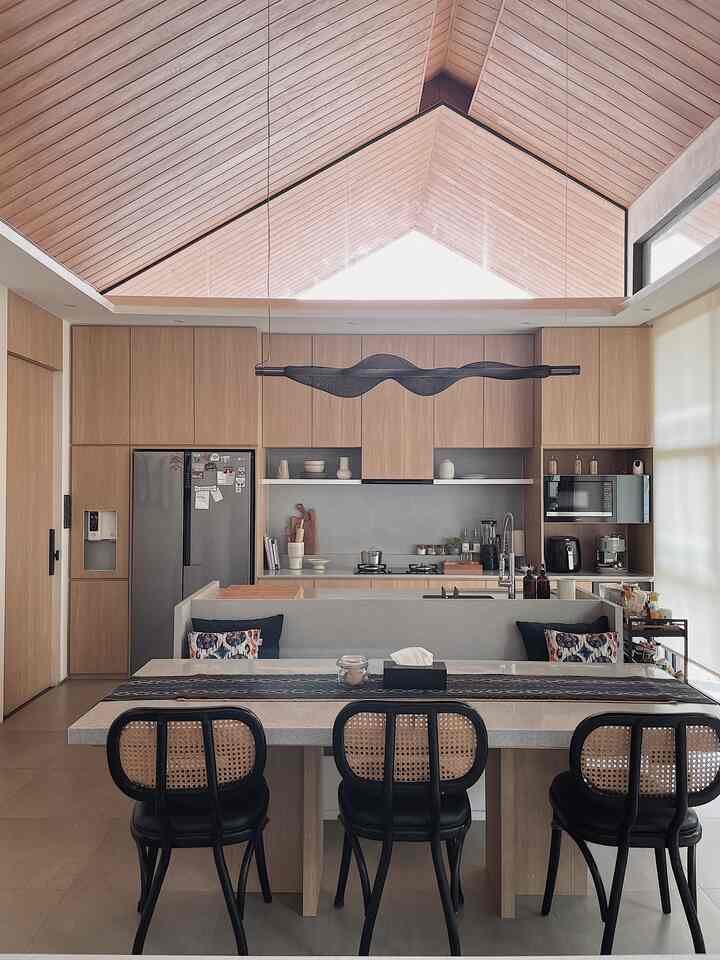Bright wood tone and black accents define the dining room and kitchen space with a high vaulted ceiling enhancing openness