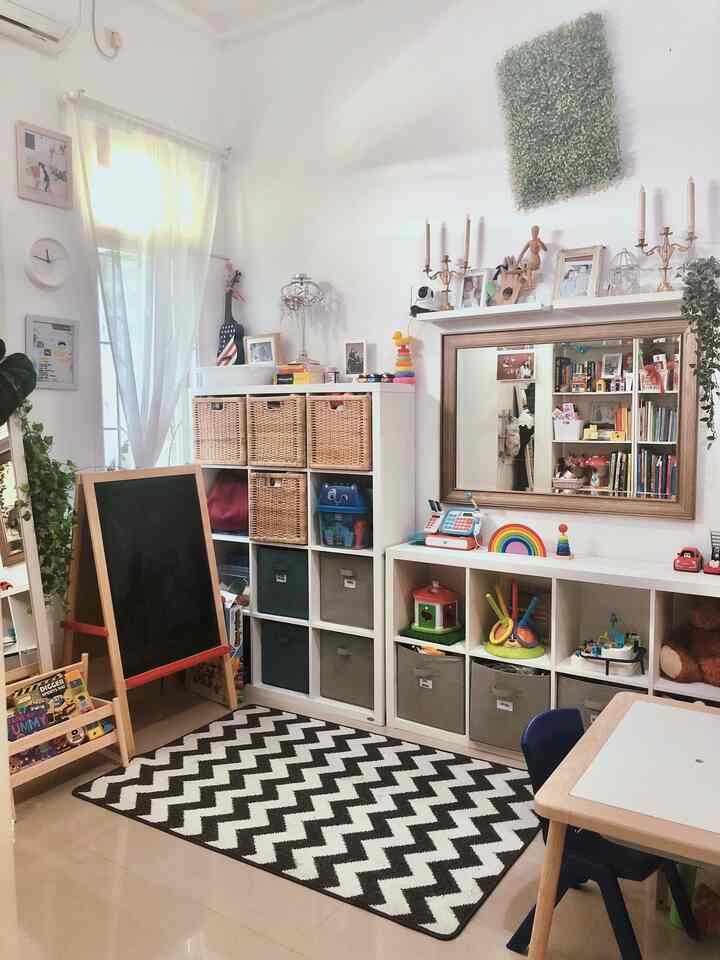 White-themed kids' room featuring storage units, children's desk, toys, and wall decor creating a cozy atmosphere