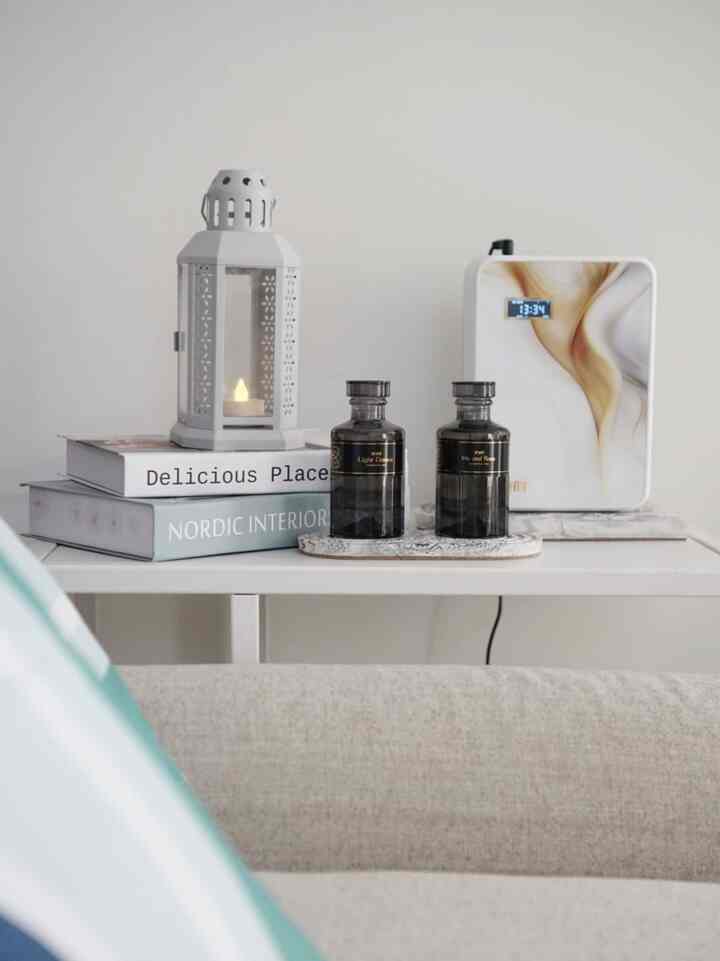 White and natural-toned living room coffee table featuring diffuser and candle with an Instagrammable minimalist vibe