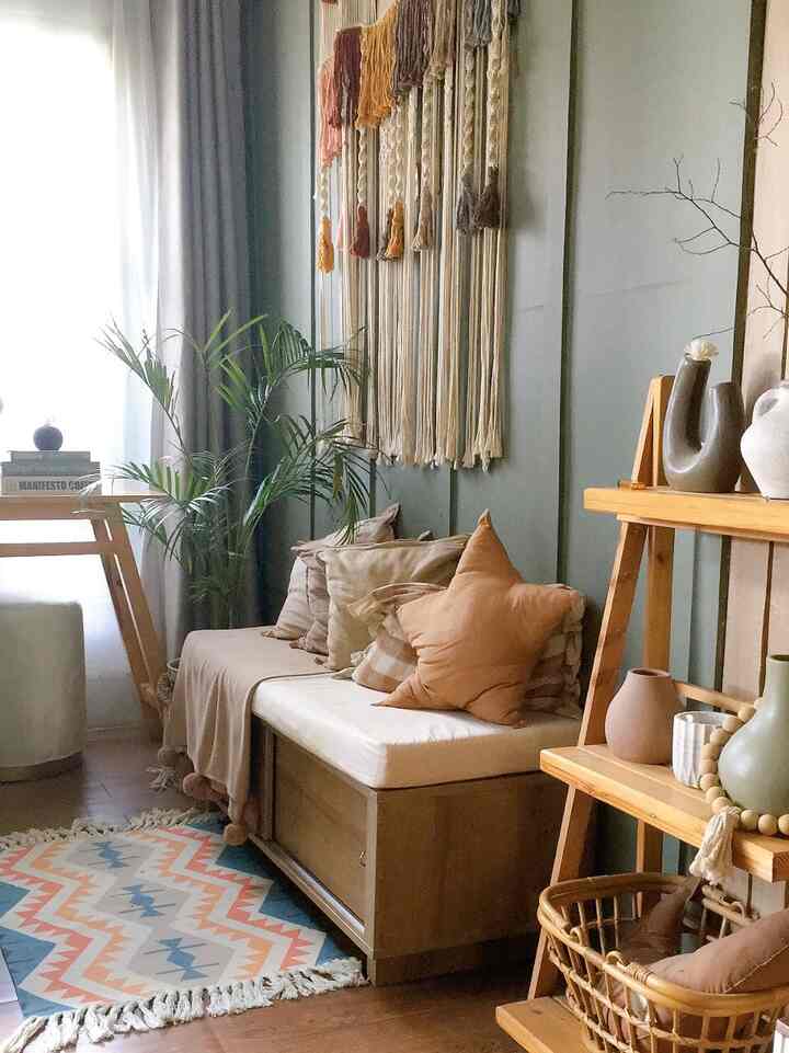 Natural wood-toned single household living room featuring a sofa bed, plants, and curtains creating a cozy atmosphere