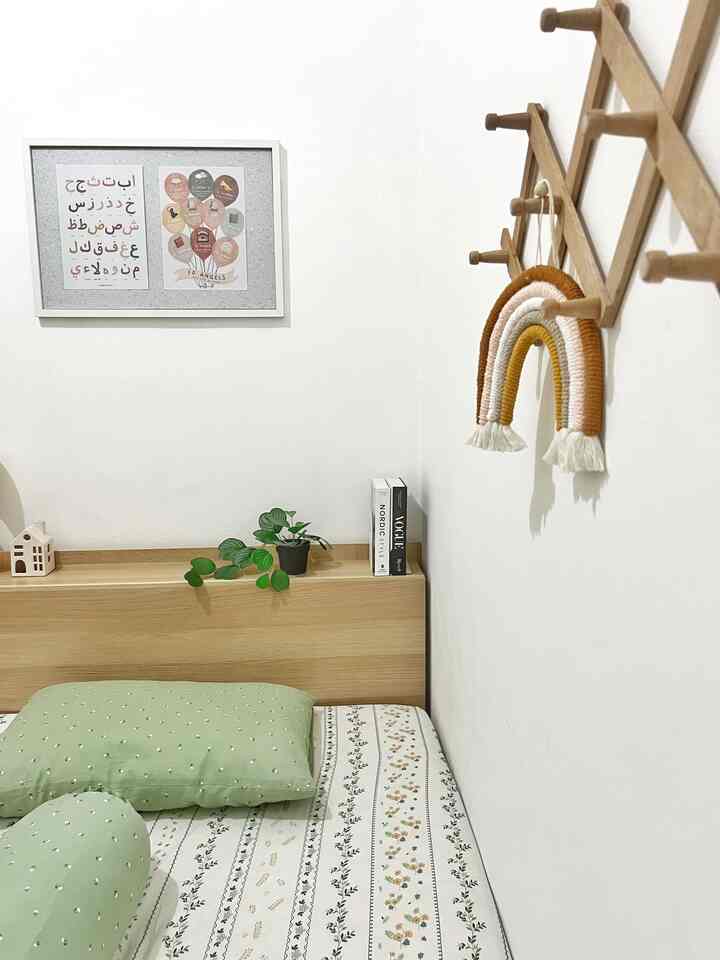 White-walled kids' room with wood tone bed, featuring educational poster and green pillows creating a cozy atmosphere