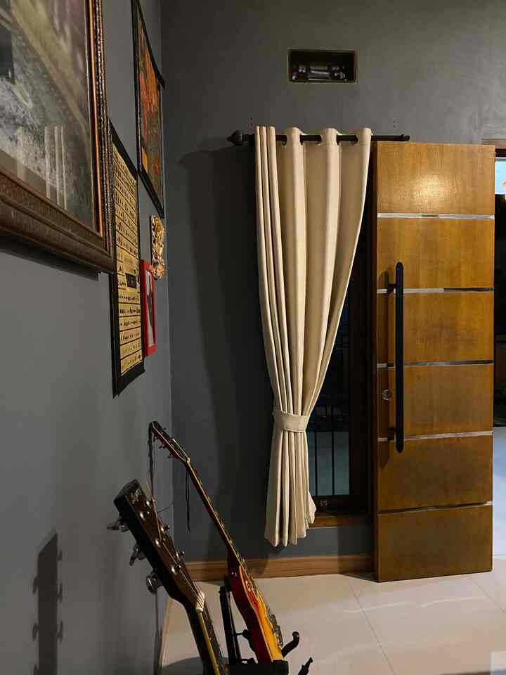 Entrance space with black walls and beige curtains, featuring two guitars on the left creating a musical atmosphere